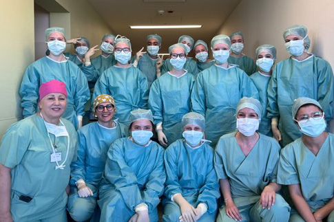 Ein Gruppenfoto: Darauf zu sehen sind fünfzehn Mädchen und Frauen in blauer OP-Kleidung