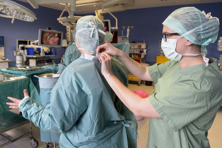 OTA bindet Kittel von Arzt im OP zu im Klinikum Saarbrücken