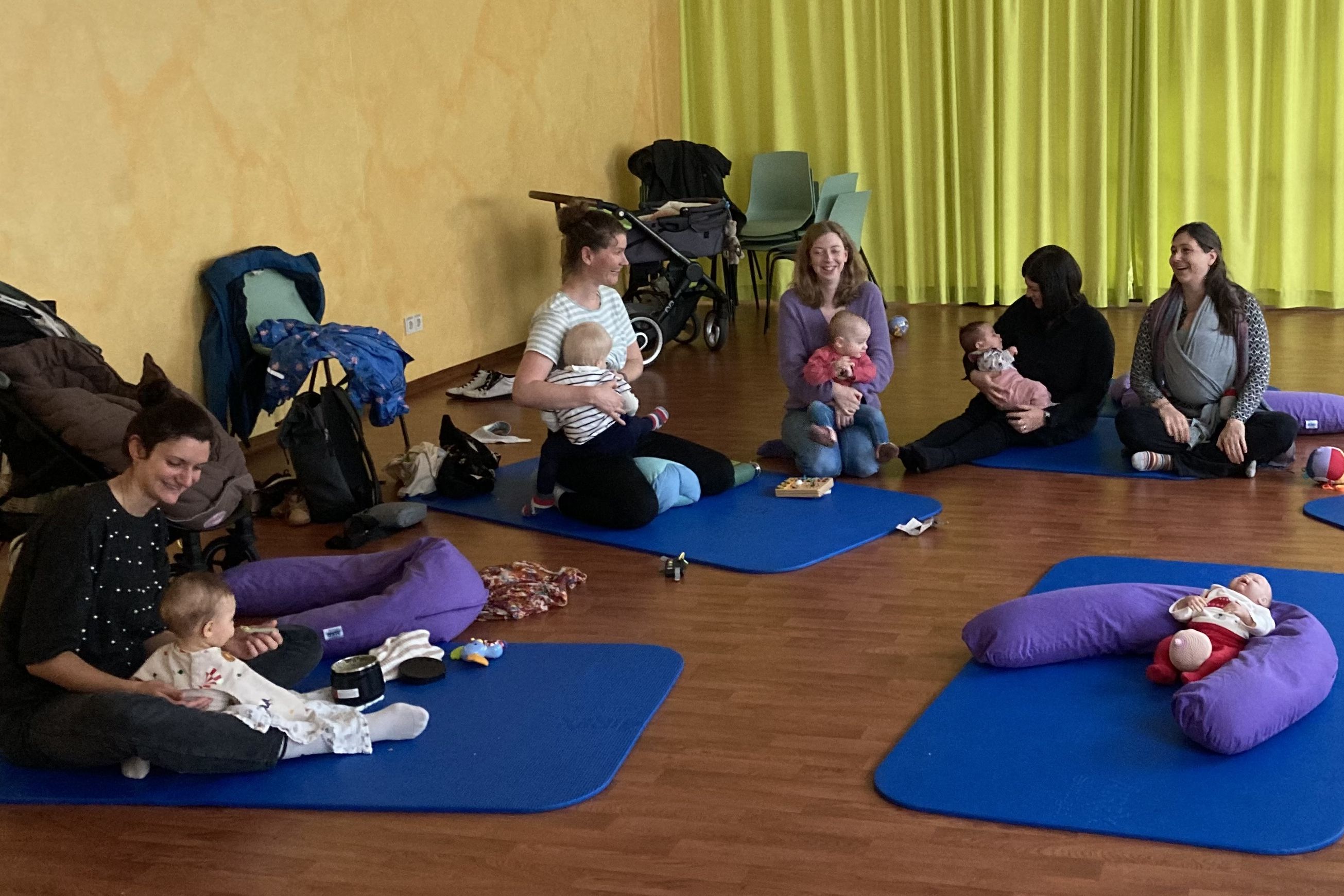 Einige Mütter sitzen mit ihren Babys im Kreis und tauschen sich aus.