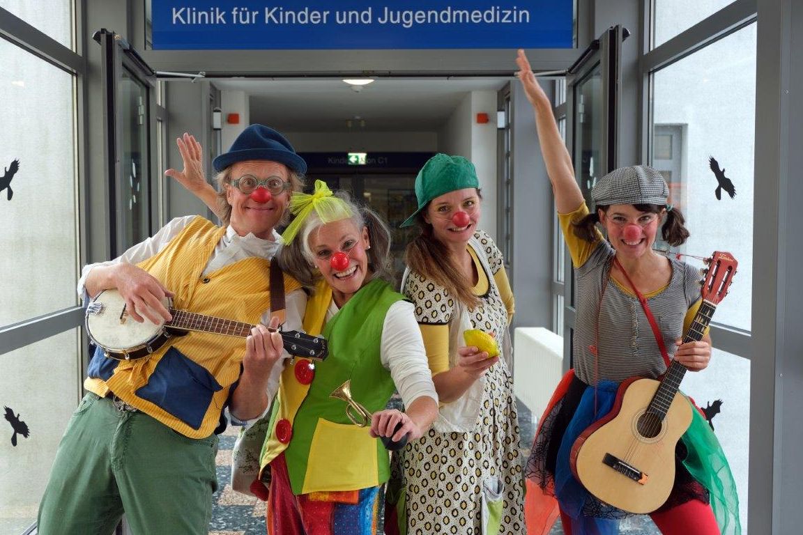 Gruppenfoto der Klinikclowns vor dem Eingang zur Kinderstation der Klinik für Kinder- und Jugendmedizin