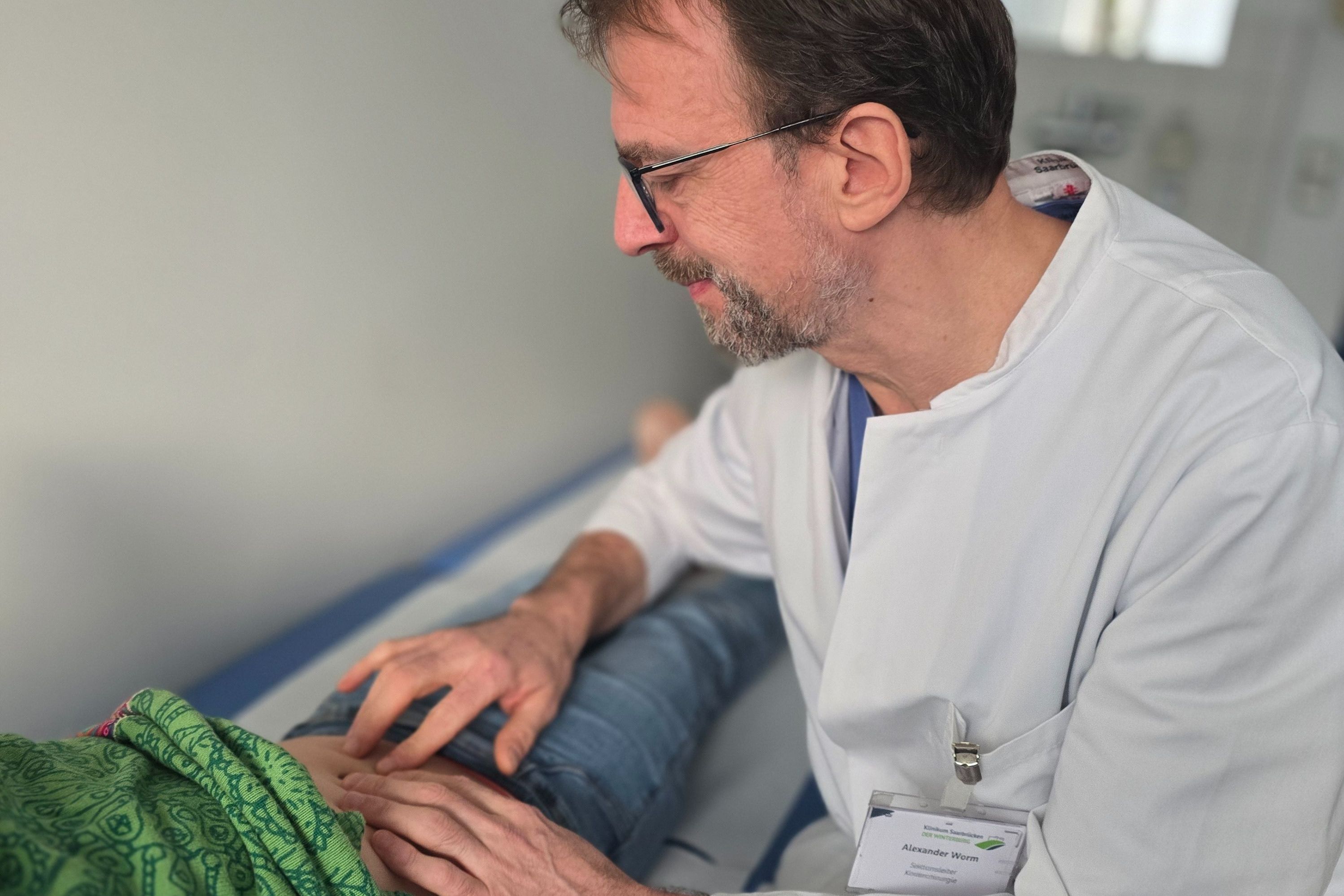 Ein Kinderarzt tastet den Bauch eines Kindes ab.