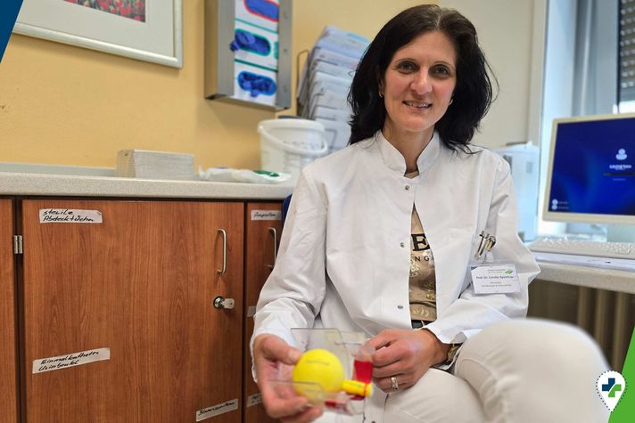 Prof. Dr. Carolin Spüntrup sitzend in einem medizinischen Behandlungsraum mit einem Blasenmodell in der Hand