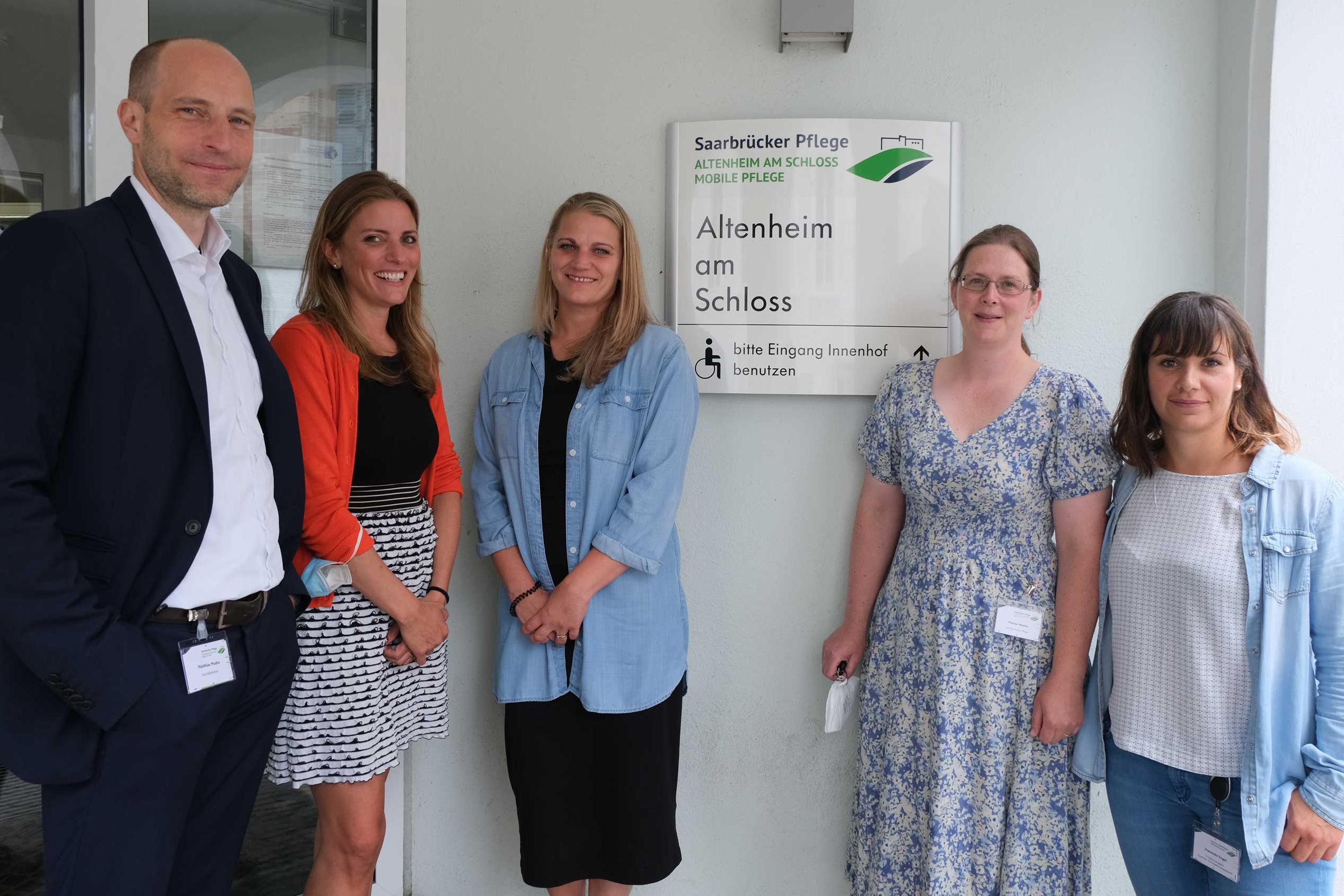 Der Geschäftsführer der Saarbrücker Pflege gGmbH, Matthias Mudra (links), steht mit den Leitungen des Altenheims (Annika Skorupa, Nelly Brosig) und der Mobilen Pflege (Marion Walter) sowie der Projektverantwortlichen aus dem Qualitätsmanagement Franziska Vogel vor einem Schild mit dem neuen Logo.