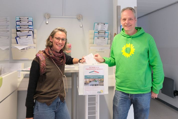 Auftakt zur Blutspendenaktion: Dominique Pegoraro (stv. Vorsitzende) und Patrick Hahl, Vorsitzender des Grünen Ortsverbands Saarbrücken-Mitte, werfen schon mal den ersten Blutspende-Scheck in die Spendenbox und sammeln für das Drogenhilfezentrum Saarbrücken.