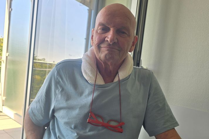 Patient Dieter Wittmann schaut in die Kamera, er sitzt auf einem Stuhl im Patientenzimmer.