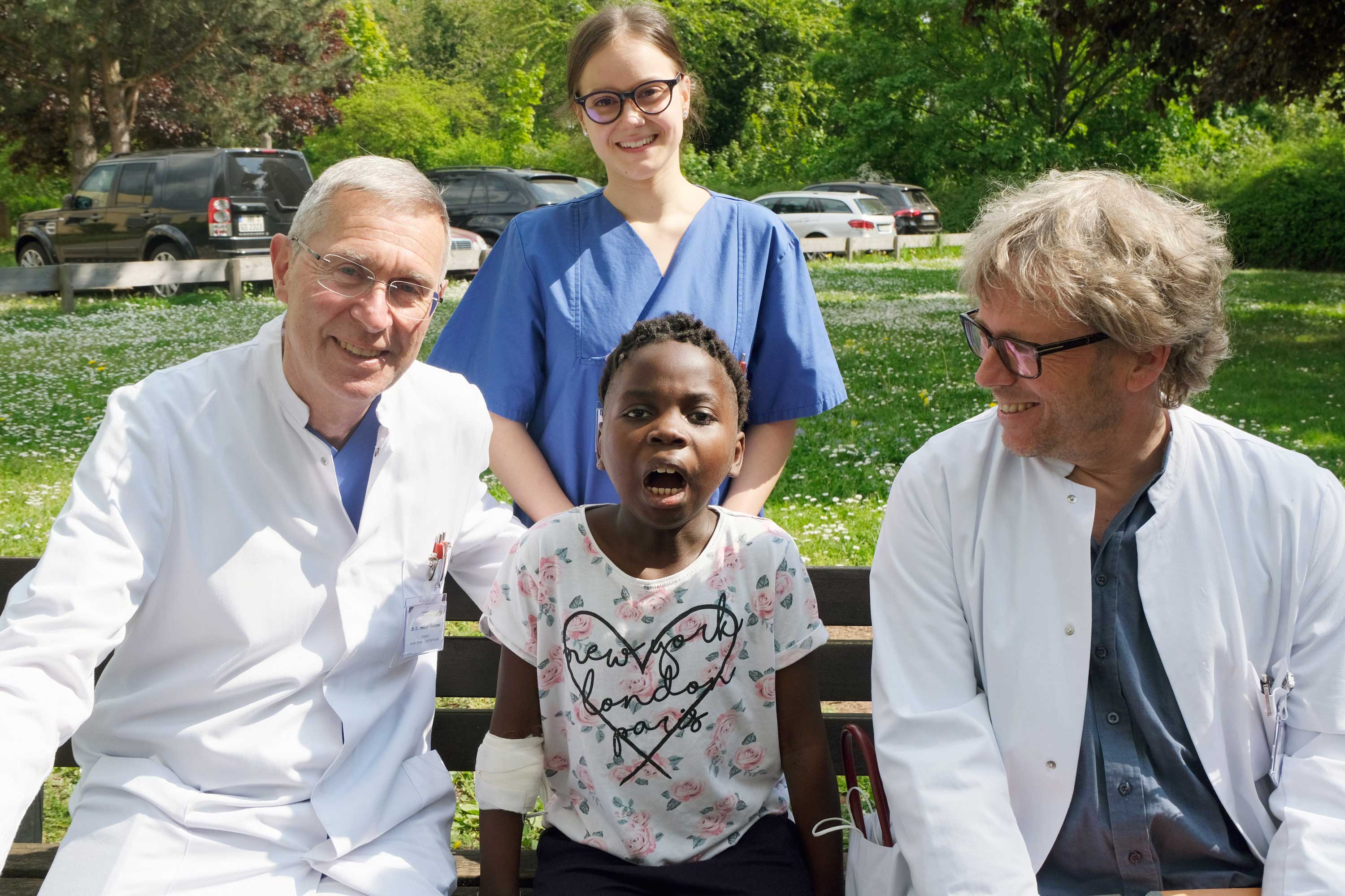 Kezia (Mitte) zeigt, wie gut sie den Mund schon wieder öffnen kann. Das ging vorher nicht. Dank des Eingriffs von Dr. Dr. Herbert Rodemer (links), Chefarzt der Klinik für Mund-, Kiefer- und Gesichtschirurgie, geht Lachen und Essen bald wieder gut. Auch Dr. Donald Wurm (rechts), kommissarischer Leiter der Klinik für Kinder- und Jugendmedizin, freut sich.
