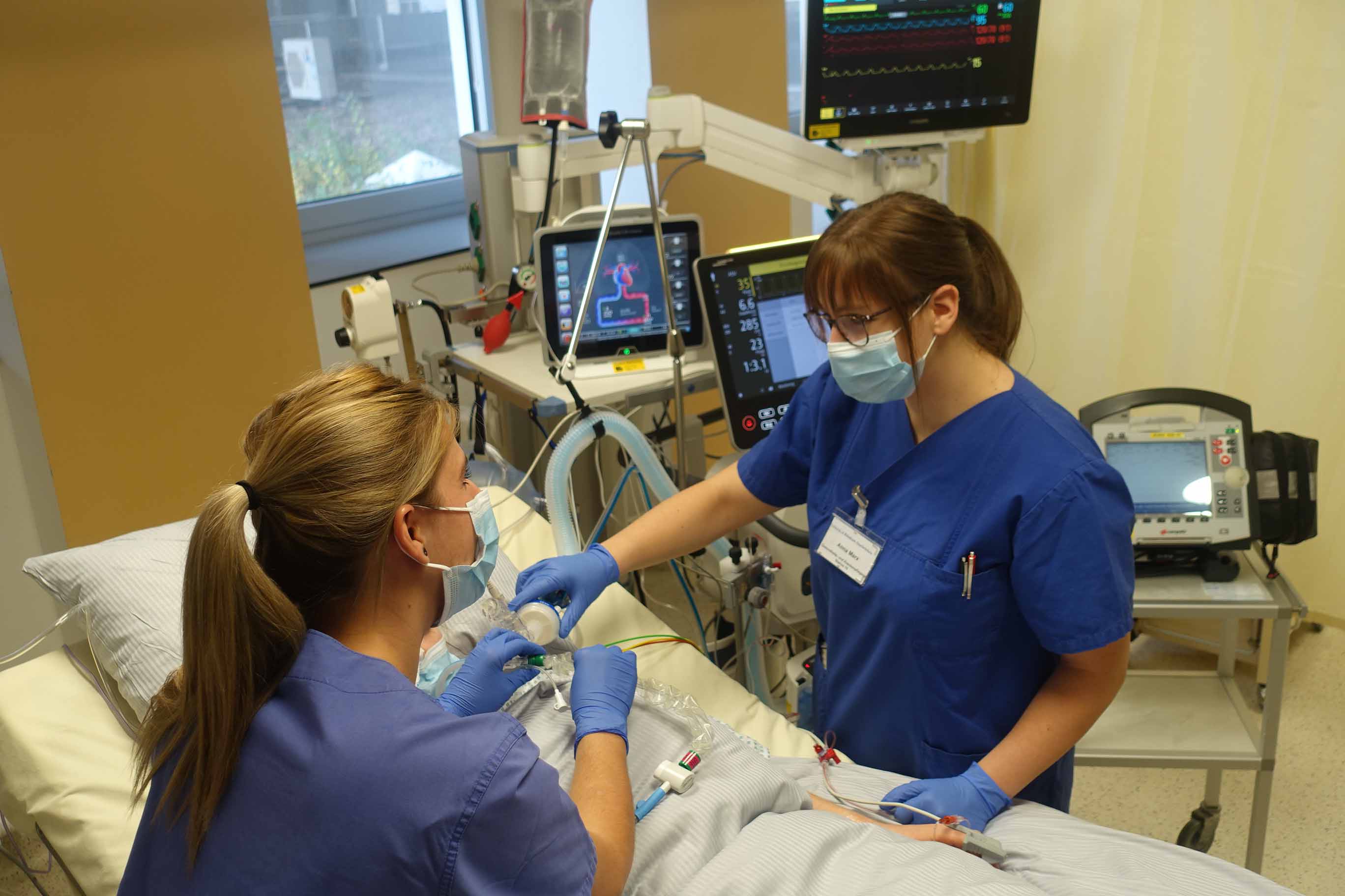 Zwei Intensivpflegefachkräfte versorgen auf der Intensivstation im Klinikum Saarbrücken einen Patienten