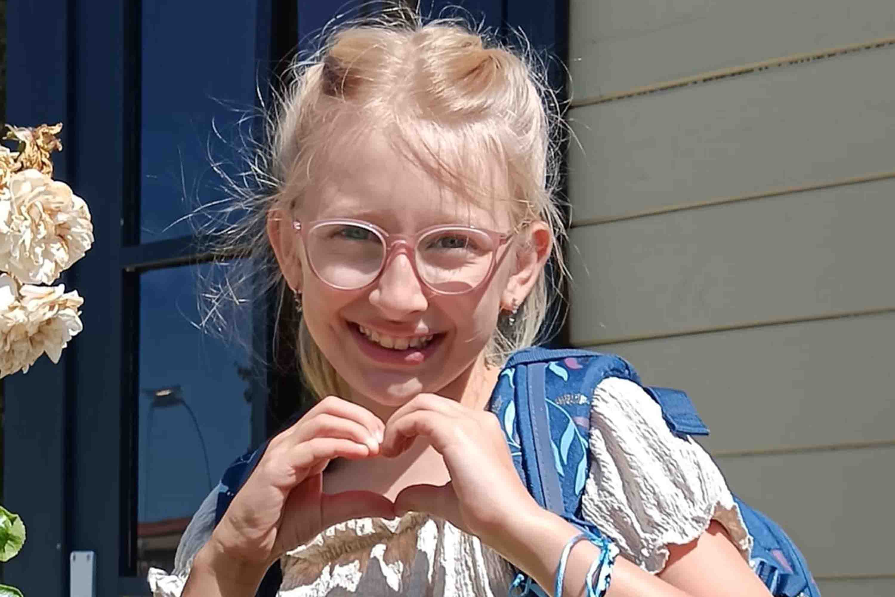 Das Foto zeigt Leonie am ersten Tag nach den Schulferien im Sommer 2025. Mit ihren Händen formt sie ein Herz.