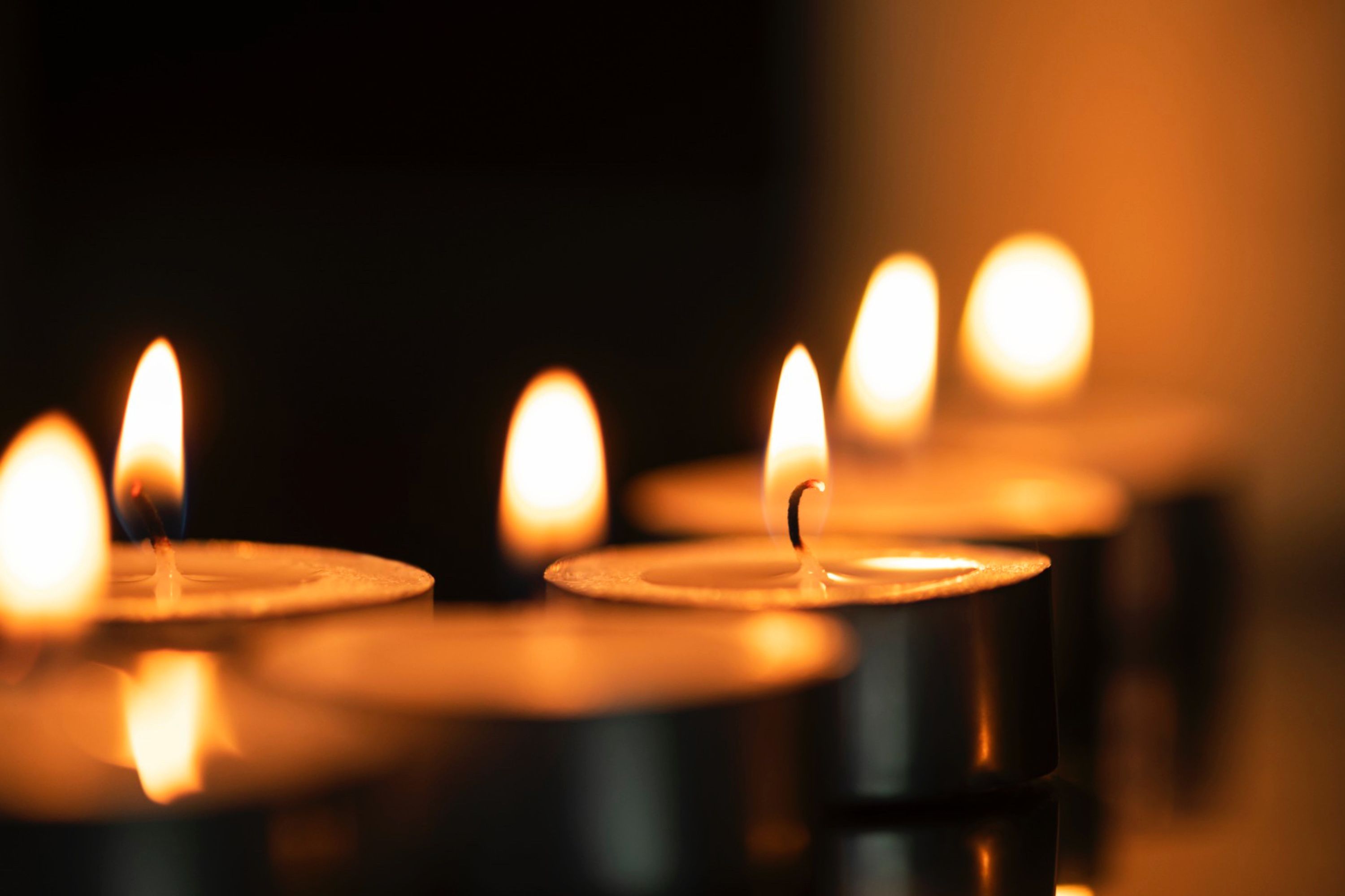 Entzündete Teelichter erhellen einen dunklen Raum.